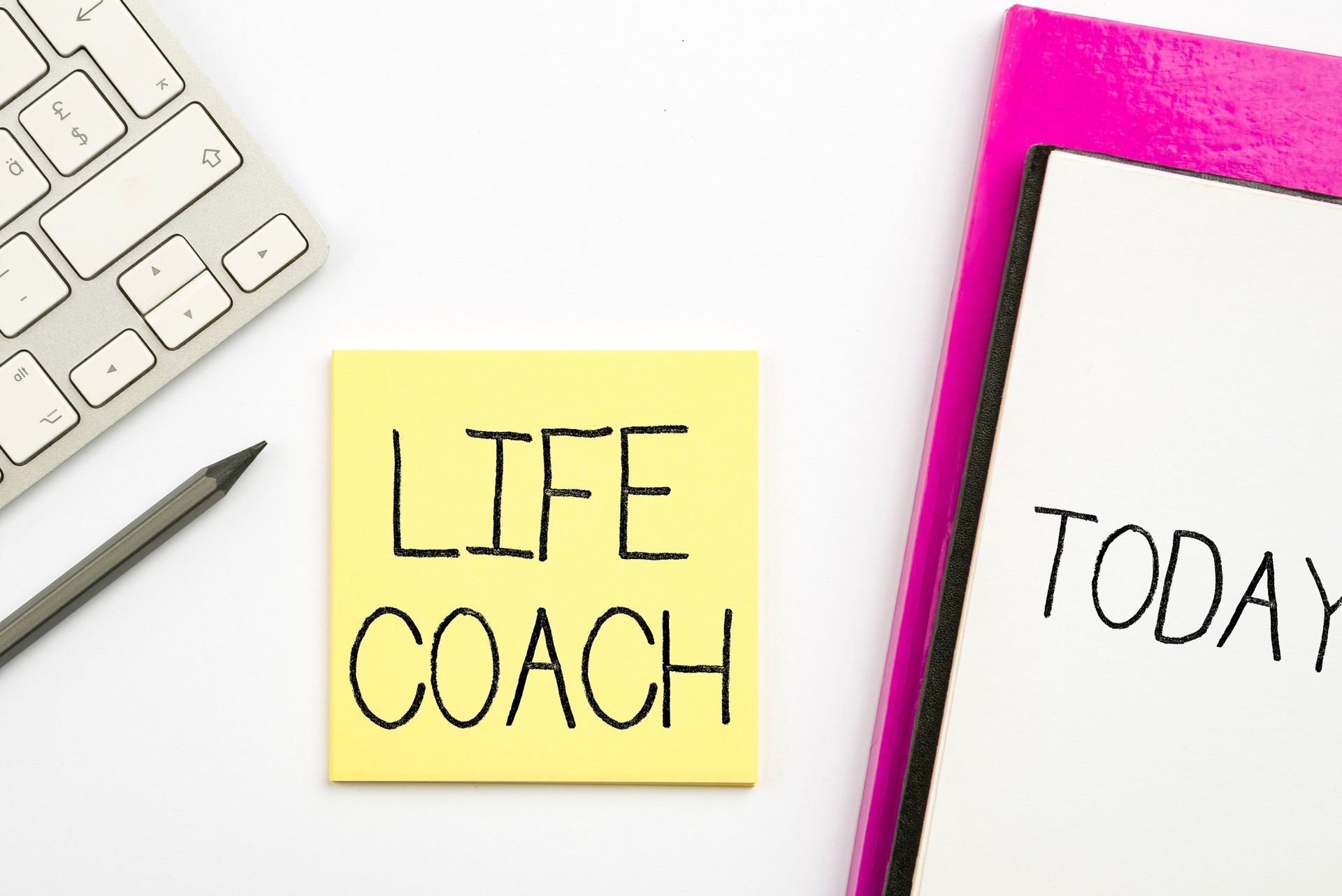 Colorful illustration of a keyboard, glasses, a notebook and a note with life coach text on it